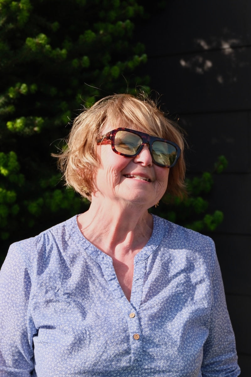 ältere Frau mit kurzen haaren trägt eine Statement Sonnenbrille mit braunen Rahmen und grünen leicht verdunkelten gläsern
