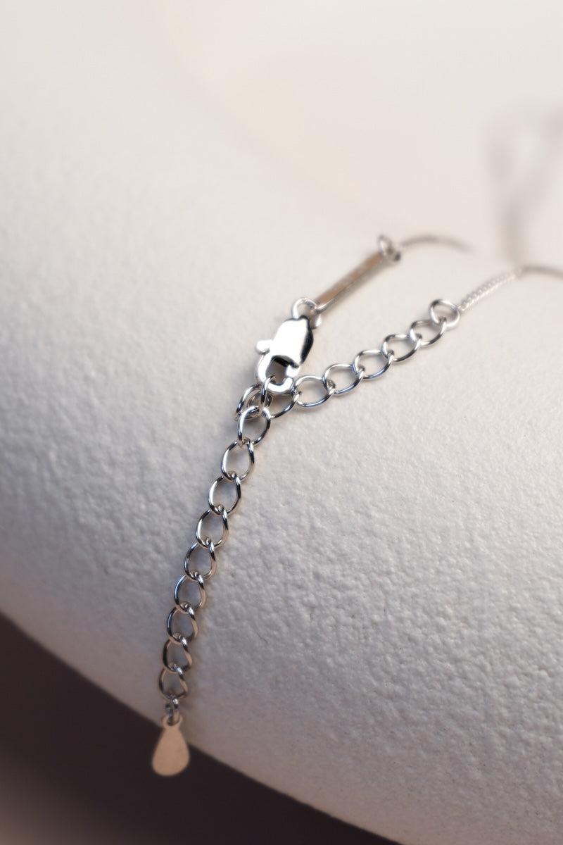 Filigrane silberne Kette unterteilt mit feinen silbernen Sterncharms ausgelegt auf einer Schale mit Karabinerverschluss