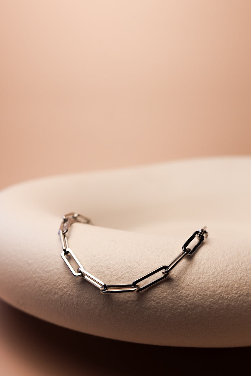 silbernes armband mit großen gliedern liegt auf weißer schale