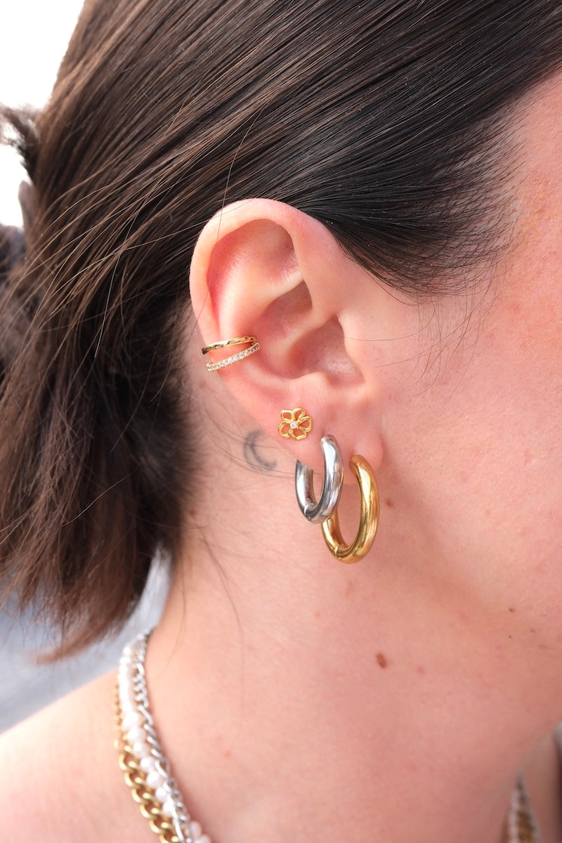 Am oberen Rand des Ohres sitzt ein earcuff aus goldfarbenem Edelstahl. er besteht aus zwei schmalen, parallel verlaufenden ringen.