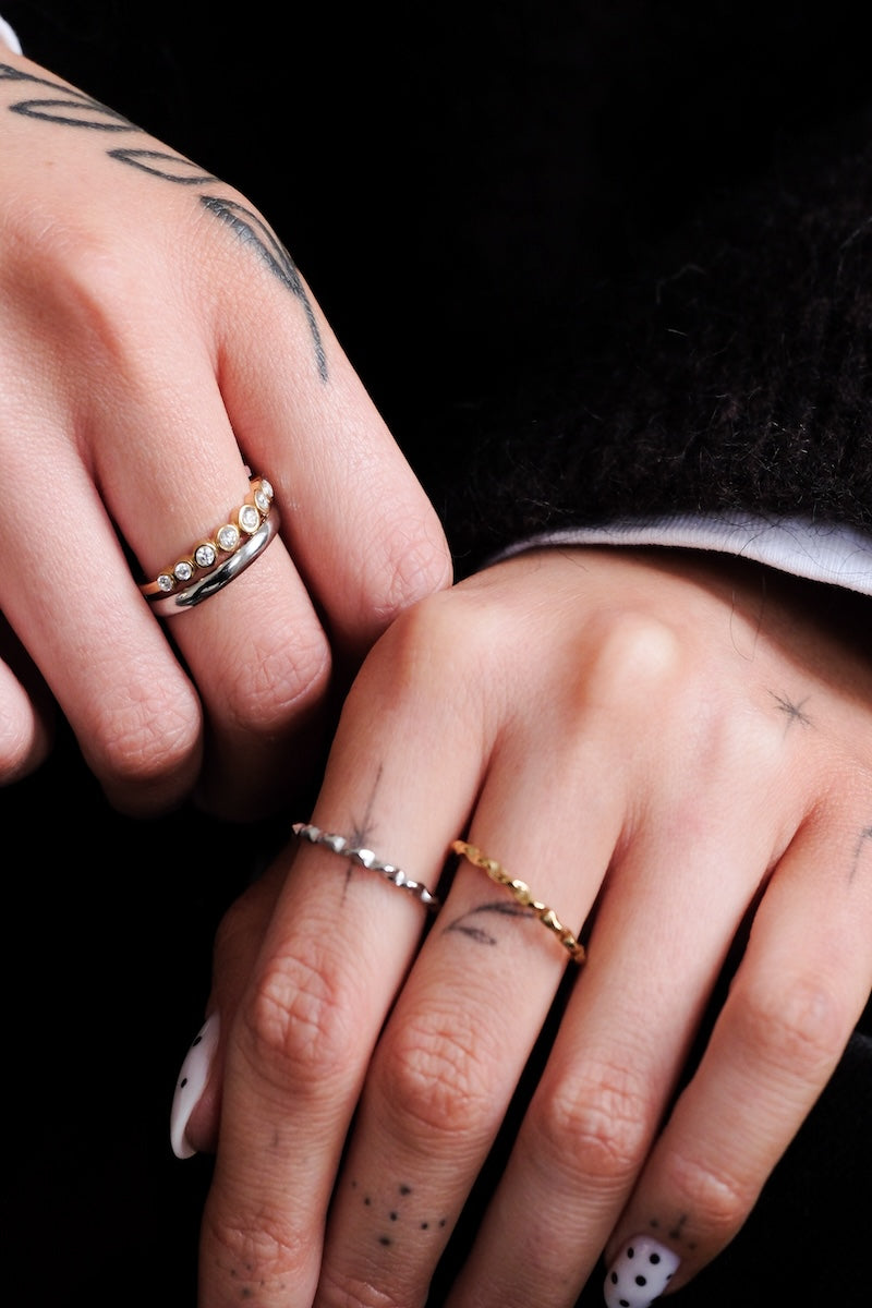 zu sehen sind zwei Hände auf der linken hand sind zwei feine Basic ringe jeweils in gold und silber und auf der anderen hand ist der be color ring wo der untere teil silber ist und der obere teil gold und mit zirkonia steinen besetzt ist