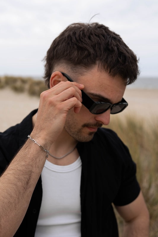 silbernes armband mit großen gliedern getragen von einem mann mit Sonnenbrille am Meer