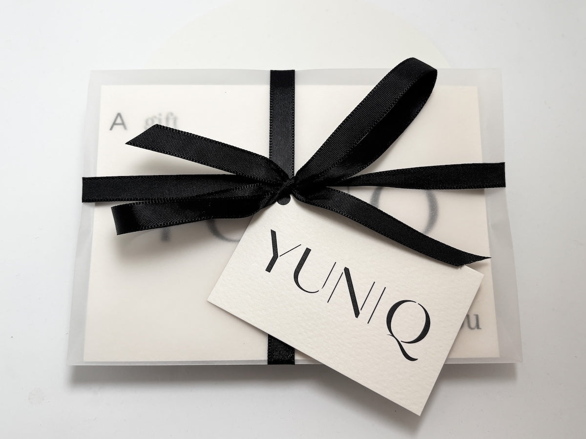 Zeigt einen Gutschein verpackt mit einer schwarzen Schleife von Yuniq