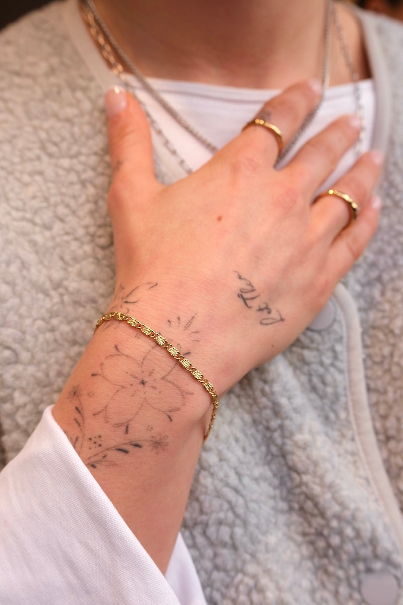 edles gold armband mit flachen eckig förmigen gliedern getragen an Handgelenk