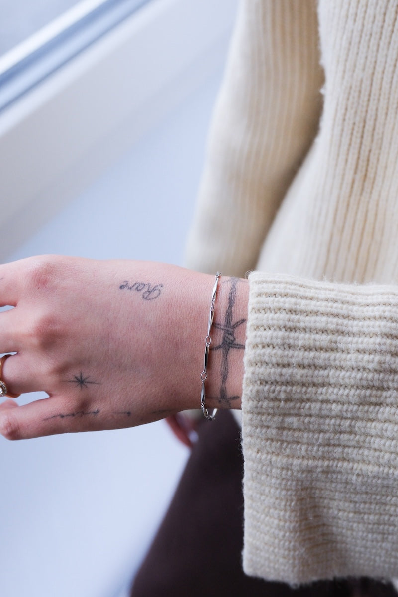 gertragenes curved Armband silber  an Handgelenk von tätowierter Frau 