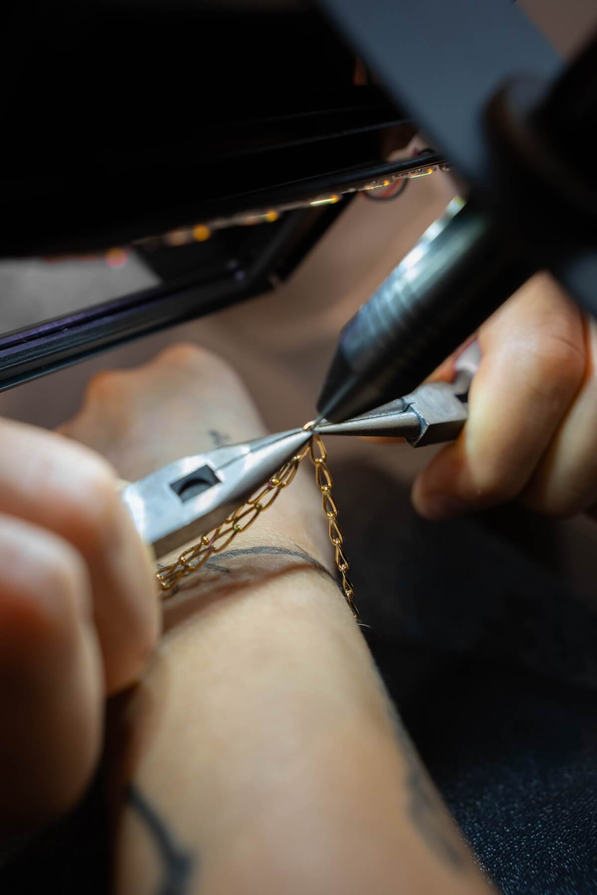 goldenes armband ohne Verschluss wird mit einer zange und einem Schweißgerät zusammengeschweißt 