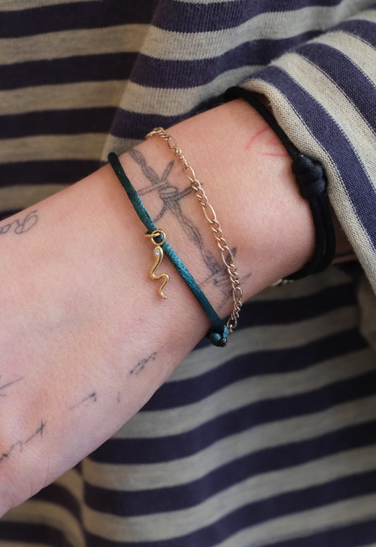 getragenes grünes friendship mit Snake charm kombiniert mit einem goldarmband an Handgelenk von einer Frau