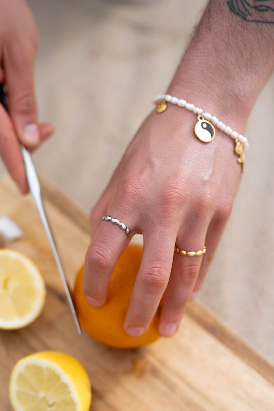perlen armband mit charms kombiniert und ringen an den fingern 