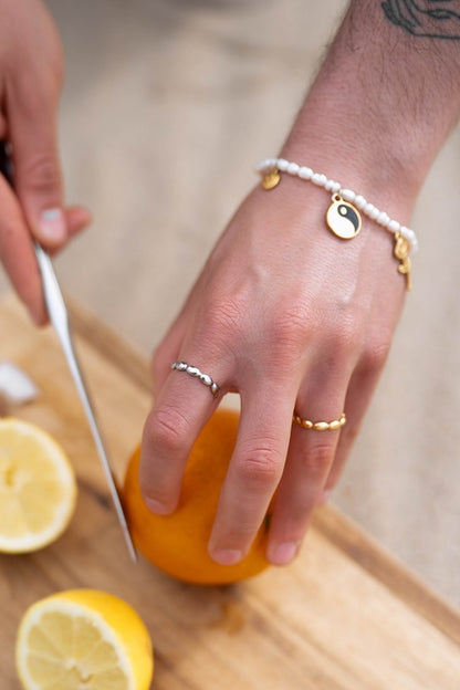 perlen armband mit charms kombiniert und ringen an den fingern 