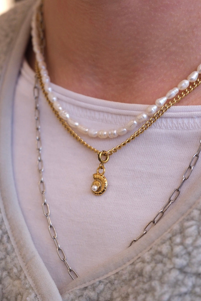 schneckenförmiger charm Anhänger mit weißer perle in der mitte kombiniert an feiner gold kette 