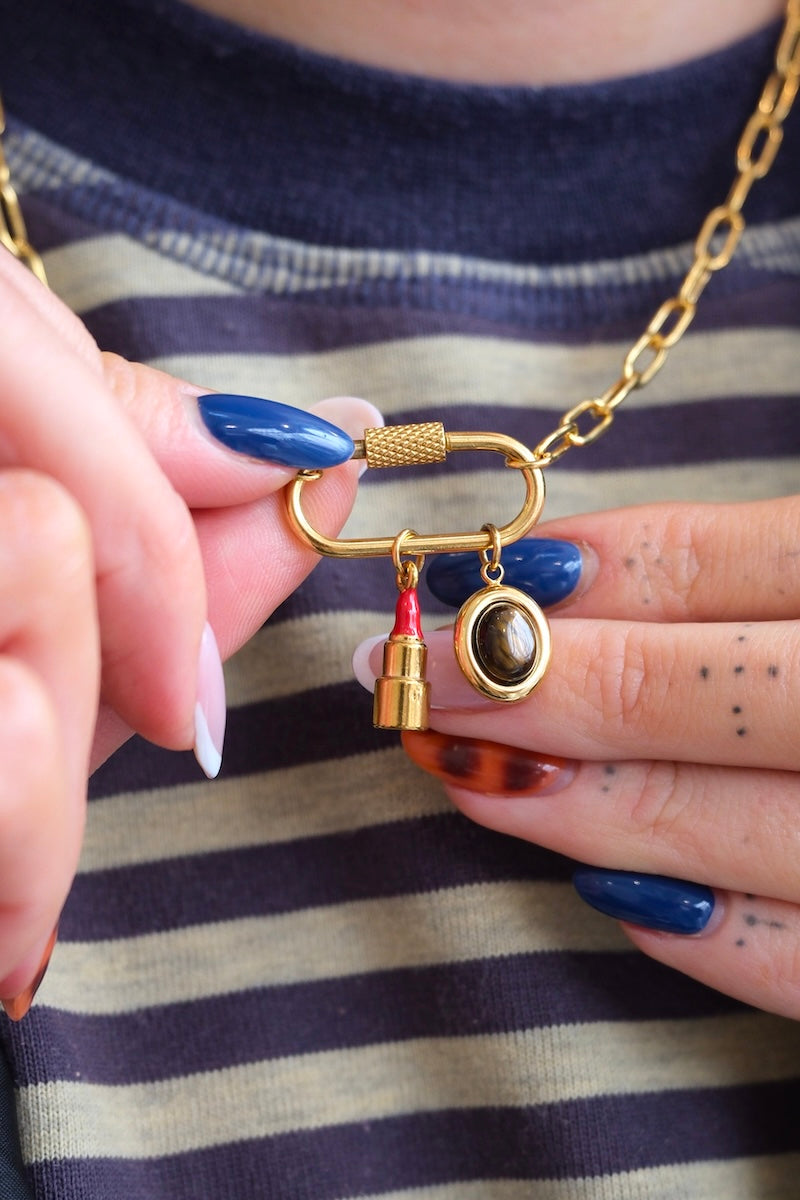 runder gold charm mit großem braunen stein in der mitte kombiniert mit einer lock kette und einem Lippenstift charm
