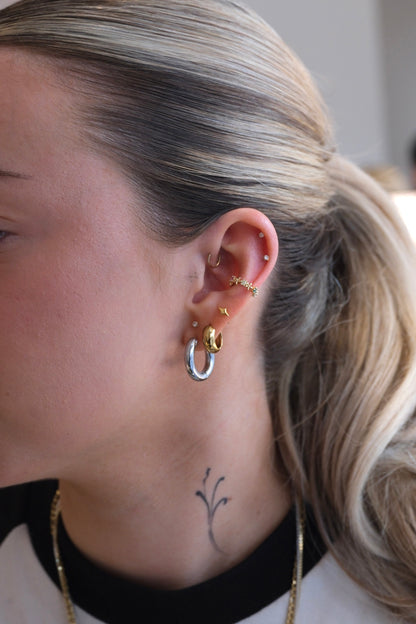 gold earcuff mit bunten steinen getragen am Ohr mit zwei hoops und vier ohrsteckern 