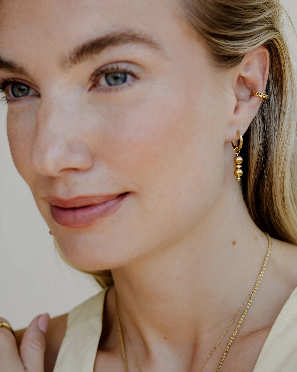 earcuff in gold getragen an einer Frau mit einem weiteren Ohrring