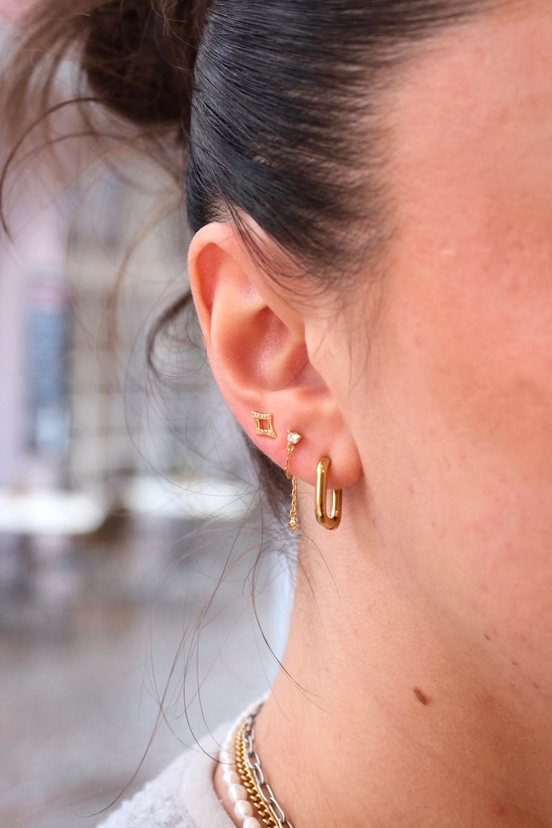 goldener eckiger hoop getragen mit zwei ohrsteckern 