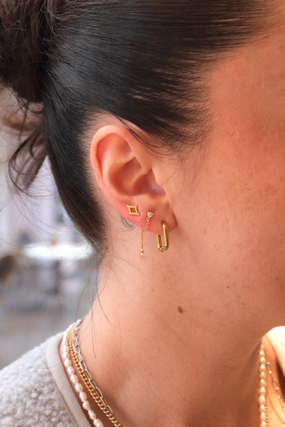 eckig getragener hoop in gold kombiniert mit zweit Ohrsteckern 