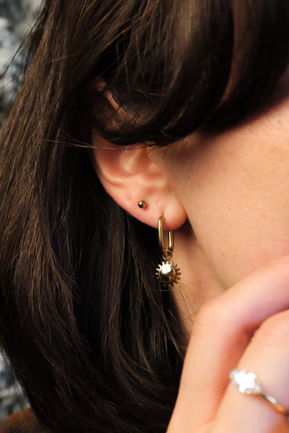 ovale getragene gold hoops kombiniert mit einem sonnen Anhänger