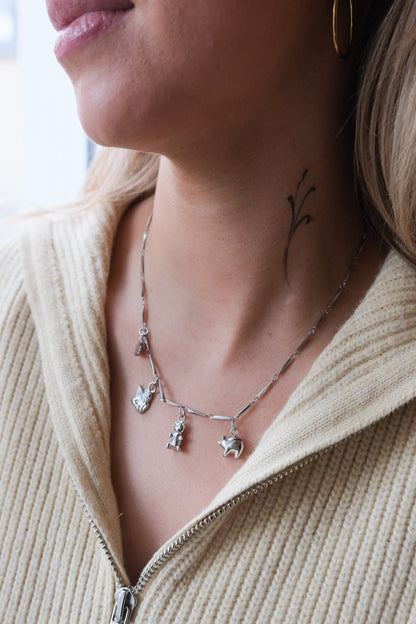 Frau mit silberne Kette bestehend aus kleinen silbernen Ösen und vier silbernen Charms 