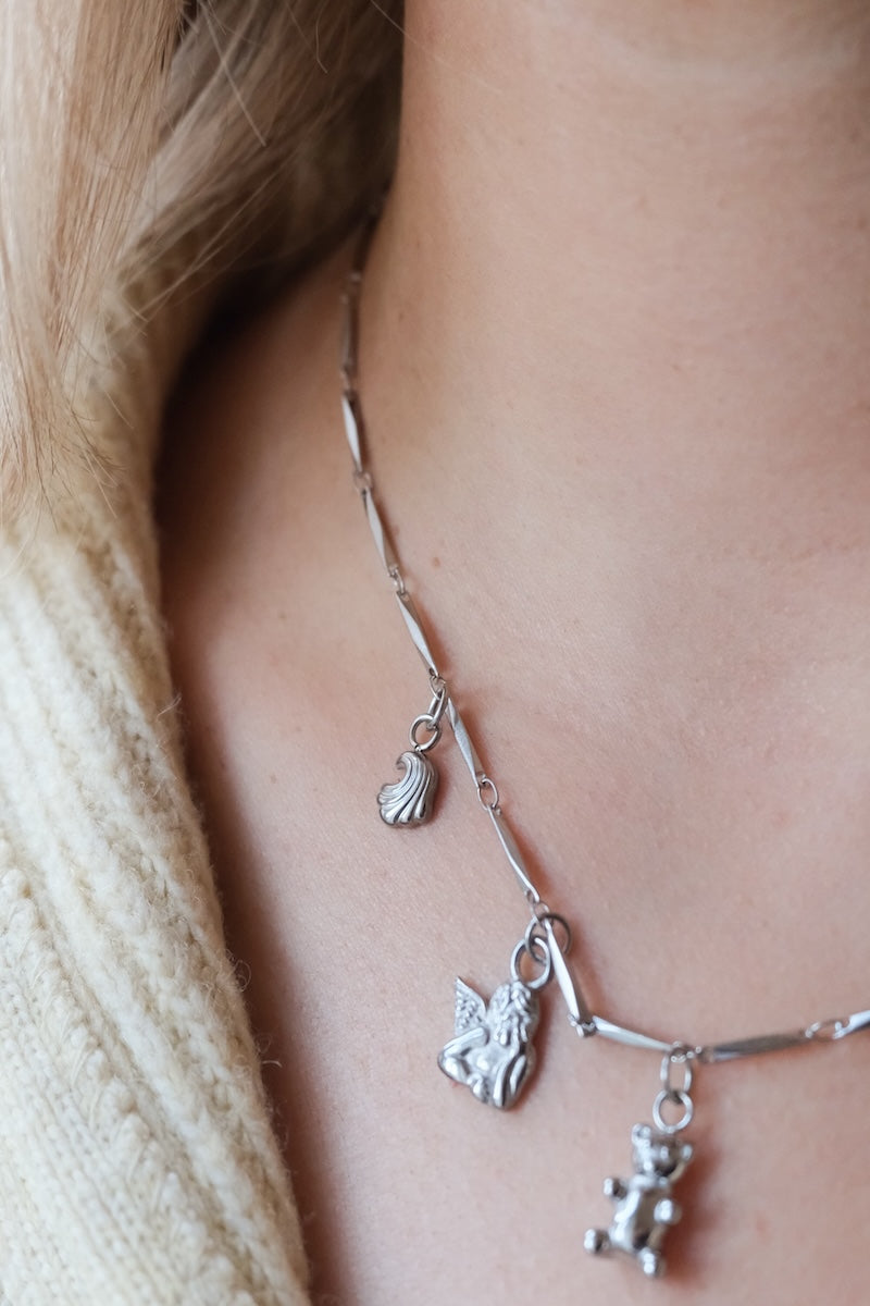 Silberne Kette bestehend aus kleinen silbernen Ösen und vier silbernen Charms