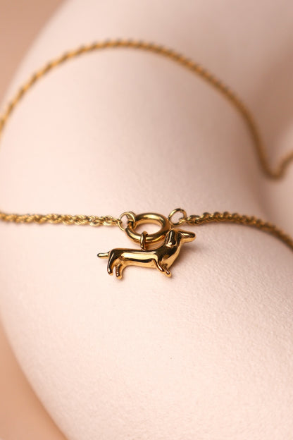 Filigrane goldene Zopfkette verbunden mit einem runden golden Ringcharm an dem ein Dackelcharm hängt
