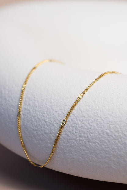 Filigrane goldene Kette unterteilt mit feinen goldenen Sterncharms ausgelegt auf einer Schale