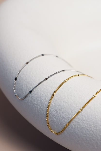 Filigrane silberne und goldene Kette unterteilt mit feinen silbernen und goldenen Sterncharms ausgelegt auf einer Schale