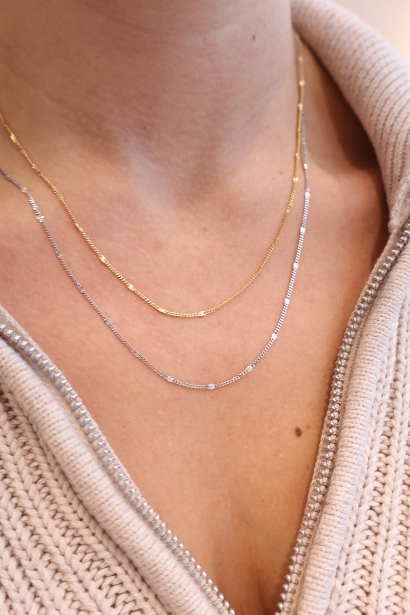 Zwei filigrane goldene und silberne Ketten unterteilt mit kleinen goldenen und silbern Sterncharms getragen am Hals