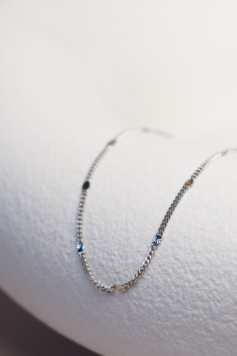 Filigrane silberne Kette unterteilt mit feinen silbernen Sterncharms ausgelegt auf einer Schale