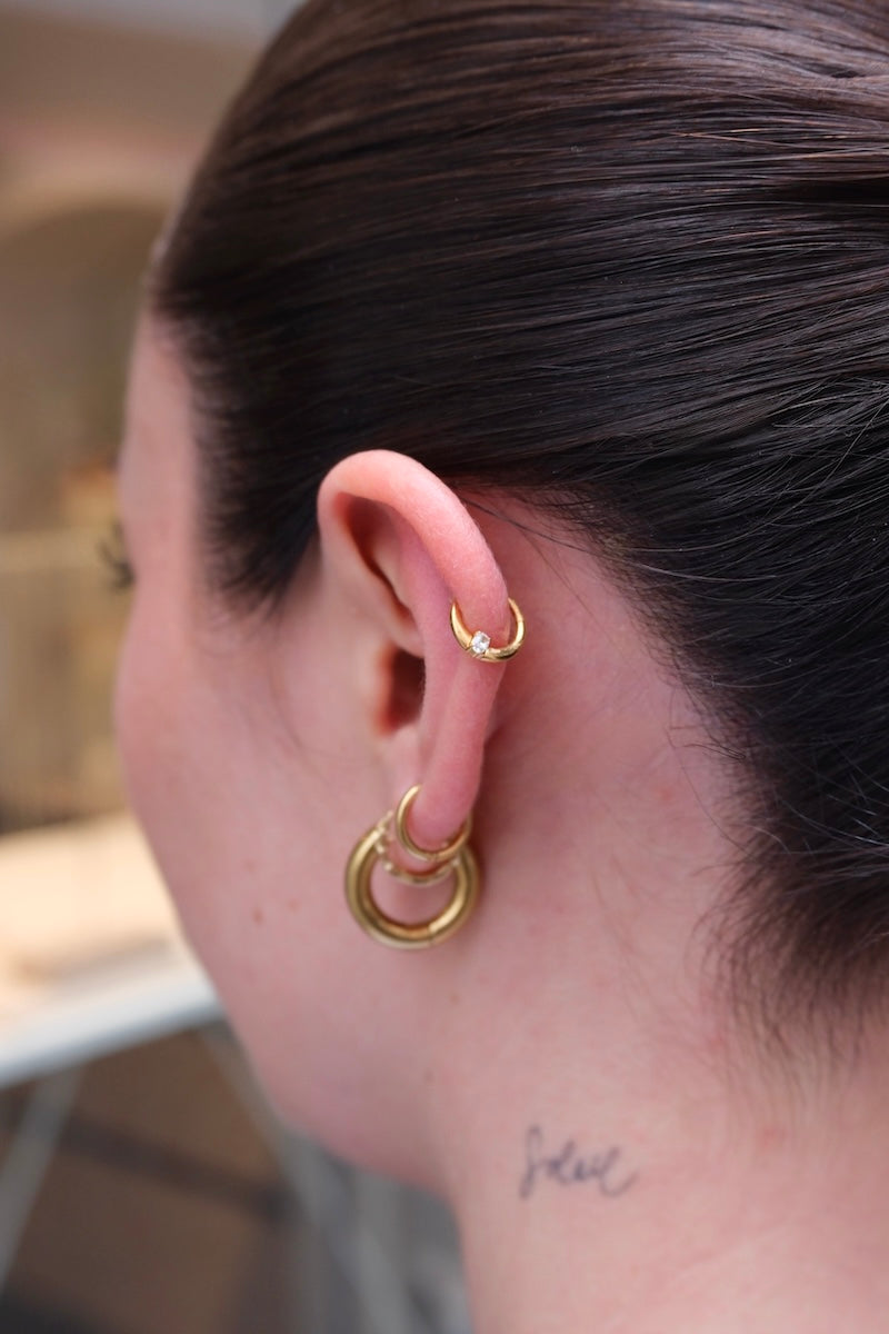 getragener piercing ring am Ohr von einer Frau mit einem steinchen drauf
