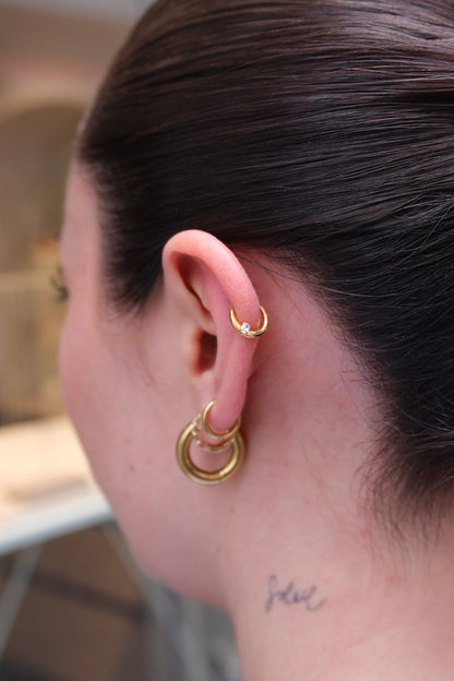 getragener piercing ring am Ohr von einer Frau mit einem steinchen drauf