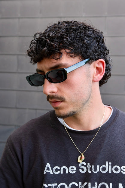 junger mann mit locken trägt schwarze Sonnenbrille mit schwarzen rahmen